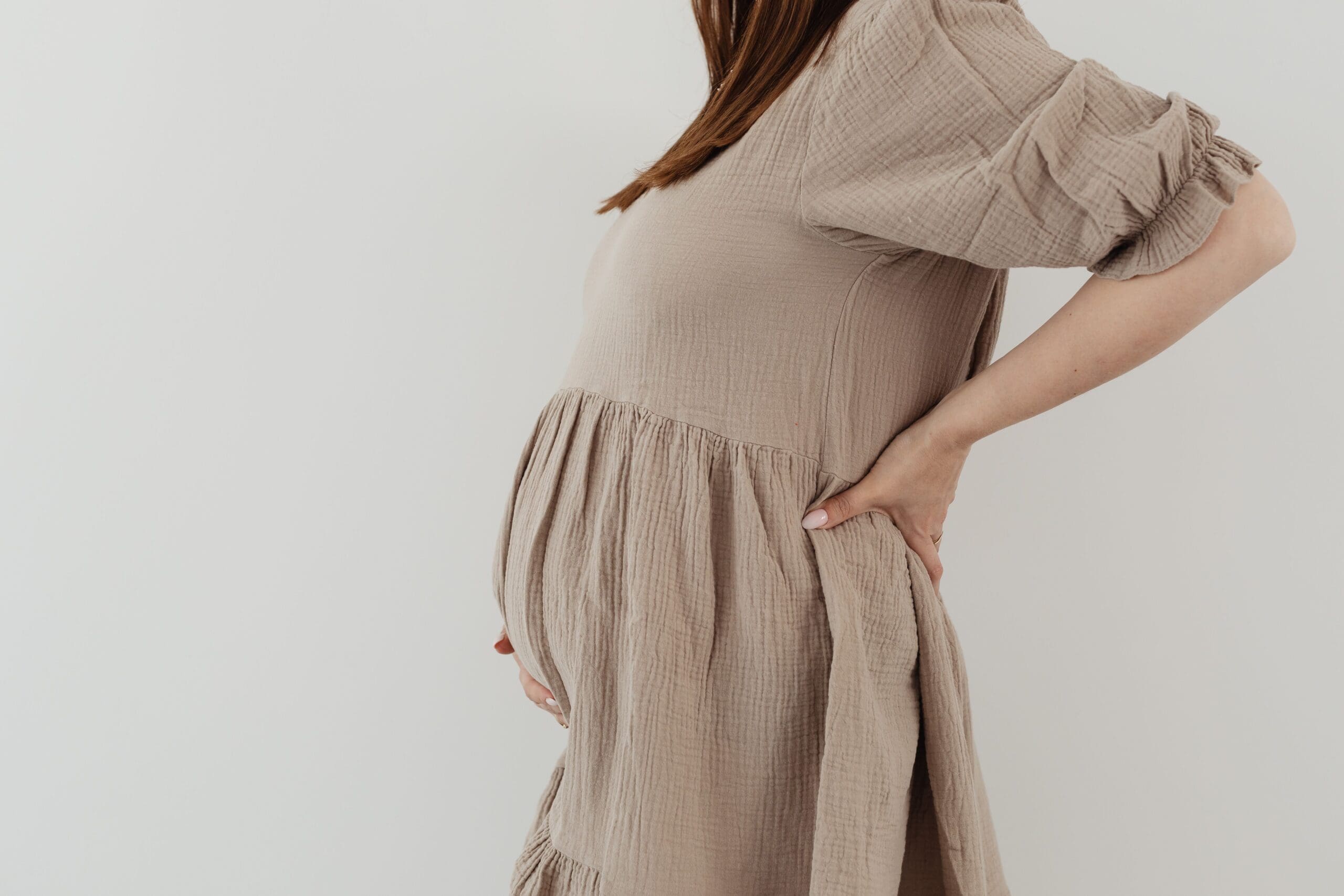 Woman with pregnant belly in a brown dress